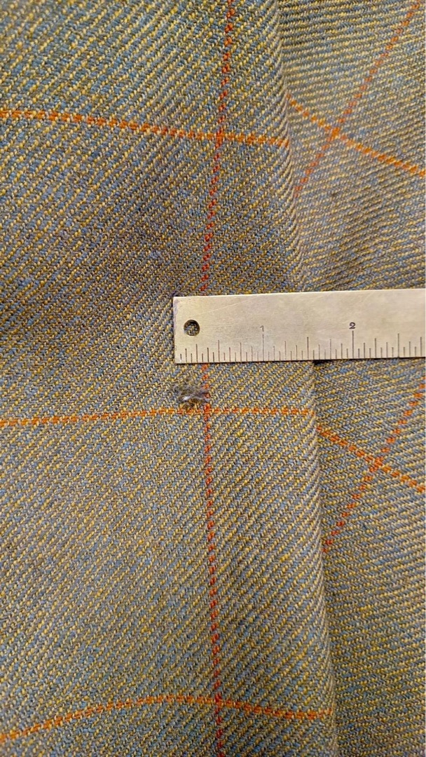 Small hole in tweed jacket measured with ruler